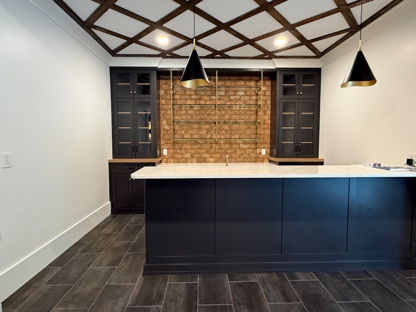 Basement bar with black cone pendants and brick backsplash