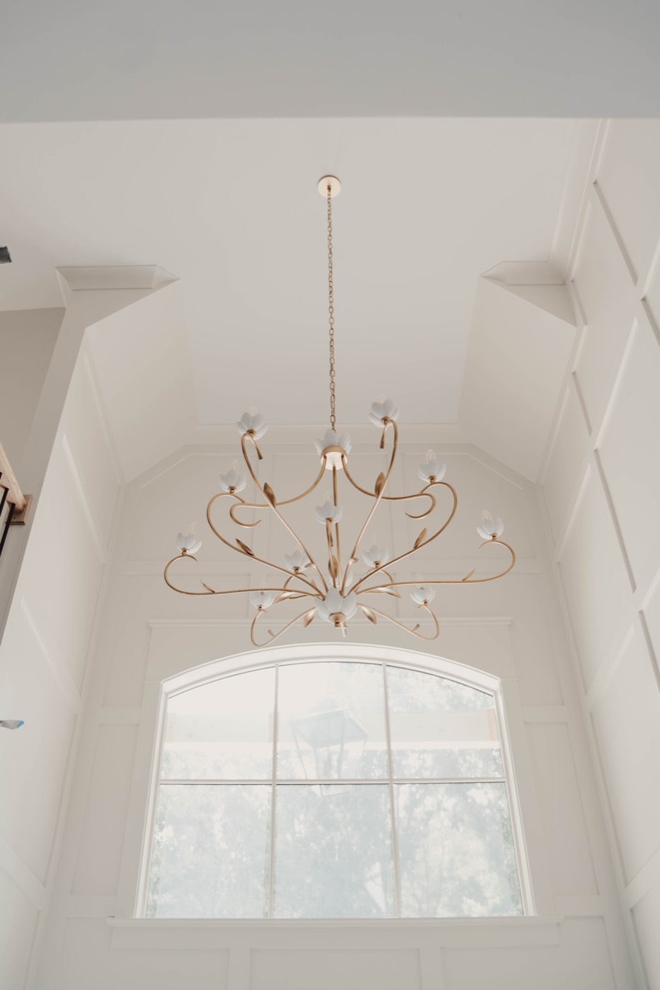 Chandelier hung in a two-story foyer with arched window